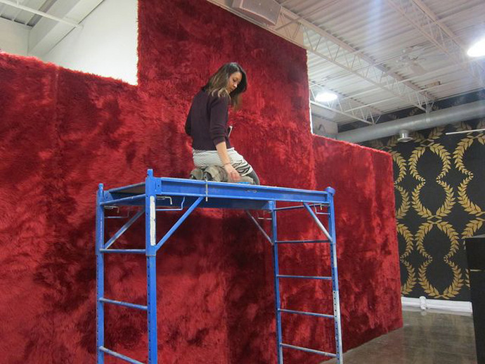 Curator Tricia Khutorestsky installing red shag carpet on the wall for Dzine - Victory (Photo courtesy of Public Functionary)